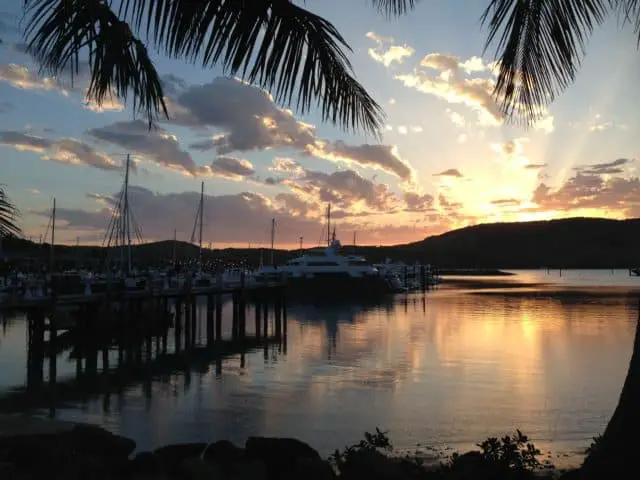 Sunset at Hamilton island; pier boats palm tree leaves