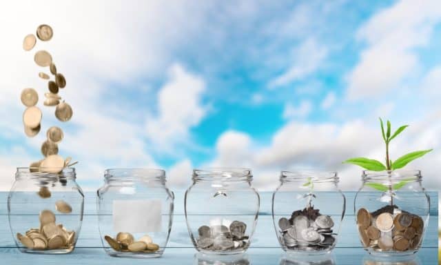 A series of glass jars with varying amounts of coins in them